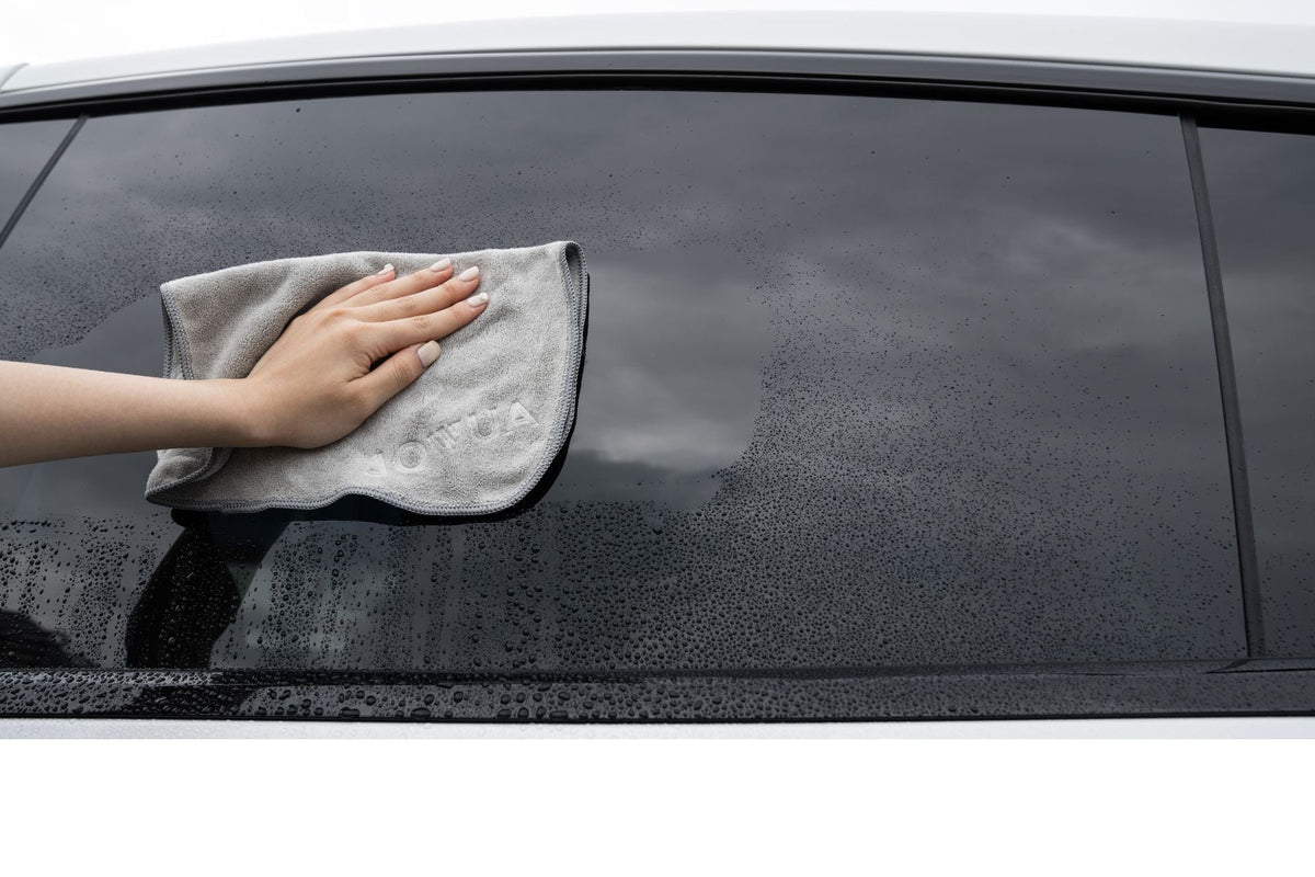 Main sèche une vitre latérale mouillée sans laisser de traces avec le chiffon en microfibre