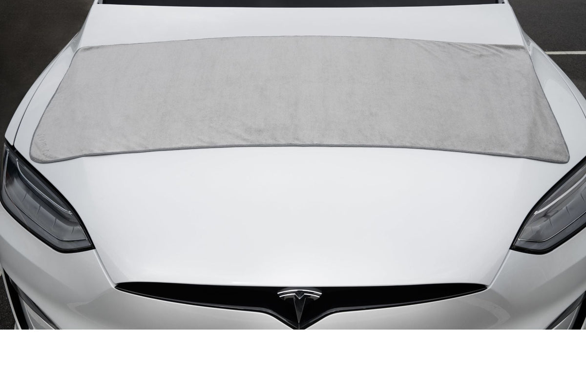 Le grand chiffon sur le capot avant d'un Tesla blanc, couvre la largeur du capot en un seul passage